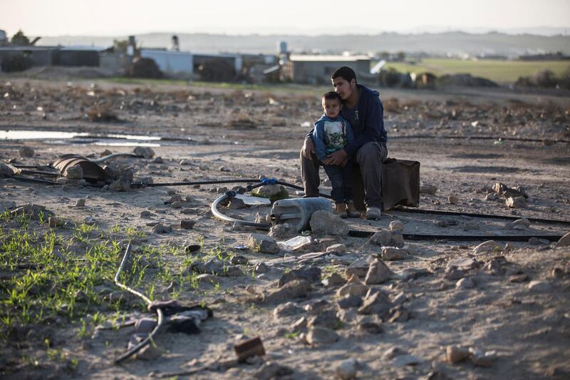 Salah El Dabashas,15, with his five year -old cousin named Omar as they  sit on a box covering an irrigation meter amongst a network of plastic irrigation pipe that supplies water to the unrecognized village of al-Poraa near the city of Arad in the Negev Desert on February 2,2018. 
A plan is being to discussed and debated to build a  giant phosphate mine thats estimated to hold 65 million tons of phosphate, by the Israel Chemicals subsidiary Rotem Amfert . Israel's Knesset is scheduled to discuss the plan which a committee of ministers have already approved, despite that the area is populated by Bedouins that fear it  will cause serious health risks and most likely evict them from their homes. (Photo by Heidi Levine for The National).
