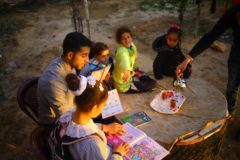 Mossab Abo Toha, who is collecting english books for his Library and Bookshop for Gaza project, reading English books with children in the garden at his family home in Beit Lahia in northern Gaza on February 20, 2017. Mohammed Abed/AFP