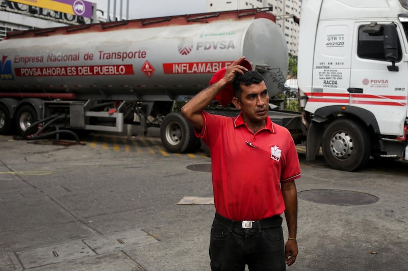 An employee of Venezuelan state owned oil company PDVSA waits as a tanker truck supplies a gas station in Caracas on March 11, 2019. Venezuela's opposition leader Juan Guaido urged lawmakers Monday to declare a "state of alarm" to pave the way for the delivery of international aid as the country's devastating blackout entered its fifth day.  / AFP / Cristian HERNANDEZ
