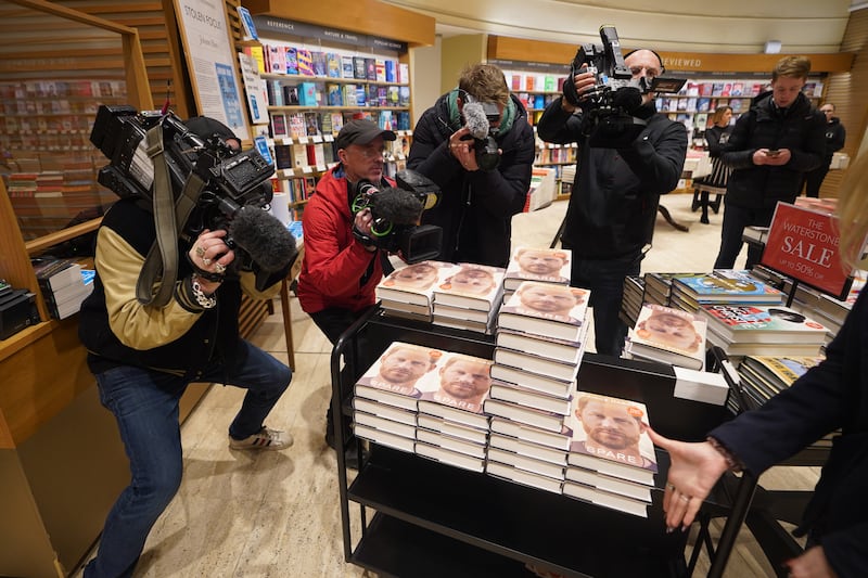 Photographers surround a trolley containing copies of Spare. PA
