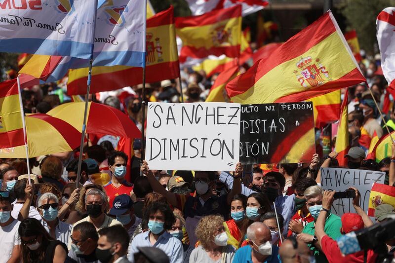 A demonstrator holds a banner reading 'Resign Sanchez' during the rally. EPA