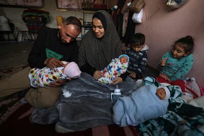 Ammar and Iman Al Masri, displaced Palestinians who fled their home in Beit Hanoun to escape Israeli bombardment, with three of their four quadruplets. AFP