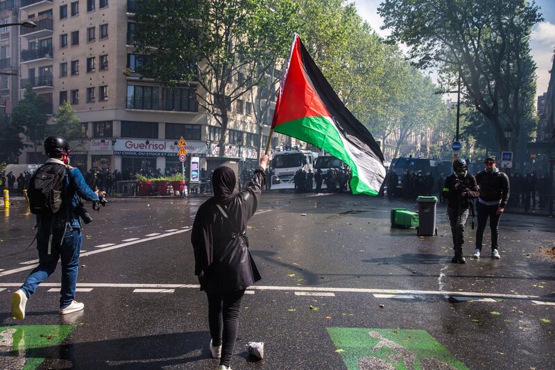 A woman holds a Palestinian flag as protesters face the anti-riot police during clashes as part of a rally organized by several associations in support of the Palestinian people, in Paris, France. EPA