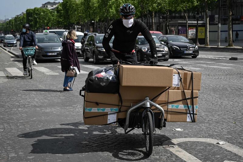 A delivery rider carries packages on the bicycle along The Champs Elysees Avenue, in Paris. AFP
