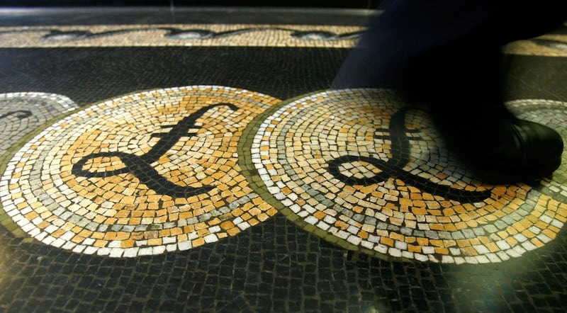 FILE PHOTO: An employee is seen walking over a mosaic of pound sterling symbols set in the floor of the front hall of the Bank of England in London, March 25, 2008.   REUTERS/Luke MacGregor/File Photo