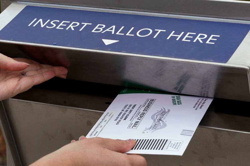 A Michigan voter inserts her absentee voter ballot into a drop box in Troy, Michigan. AP