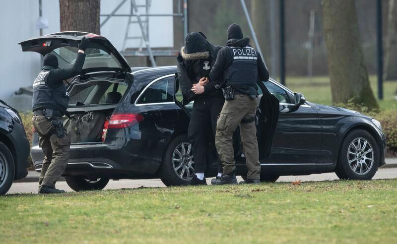 An unidentified person is brought to the Federal Supreme Court by police officers in Karlsruhe, Germany, Saturday, Feb 15, 2020. The person are one of among 12 men detained Friday in nationwide raids on suspicion of forming and supporting a â€œright-wing terrorist organization.â€ A federal judge on Saturday ordered the men held in investigative detention. (Uli Deck/dpa via AP)