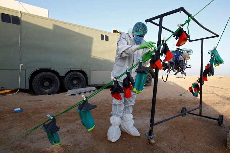 A member of the PMF, who volunteered to work in the cemetery, wears a protective suit as he hangs masks and gloves to dry them after sterilization at the new Wadi Al Salam cemetery for those who died of Covid-19). REUTERS