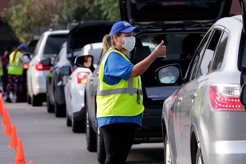 Lisa Iparrea, director of client services, gives a thumbs up as she helps direct cars through the touchless drive thru food distribution line at the West Houston Assistance Ministries, in Houston. Many people in Houston and around the U.S. live paycheck to paycheck and were caught off guard by the economic fallout from the coronavirus that initially cost the nation 22 million jobs, with 10.7 million still unemployed. AP Photo