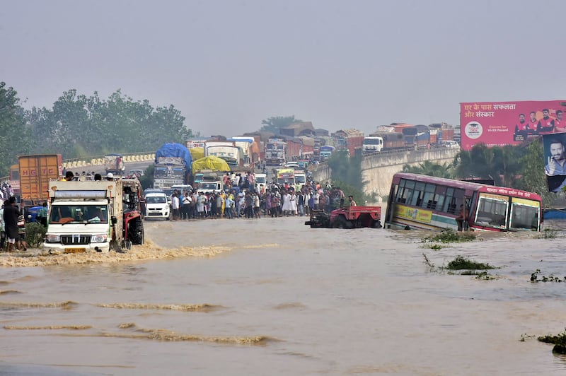 Commuters stand on a flyover, on a flooded motorway near Rampur, in India's Uttar Pradesh state, in 2021. AFP