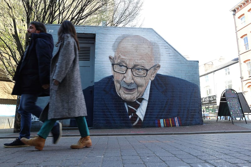 People walk past a mural of Captain Tom Moore by street artist Akse P19 in Manchester's North Quarter. AP Photo