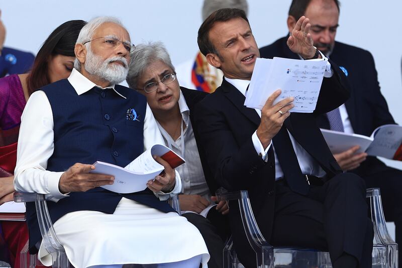 Mr Macron talks to Mr Modi during the parade. AP