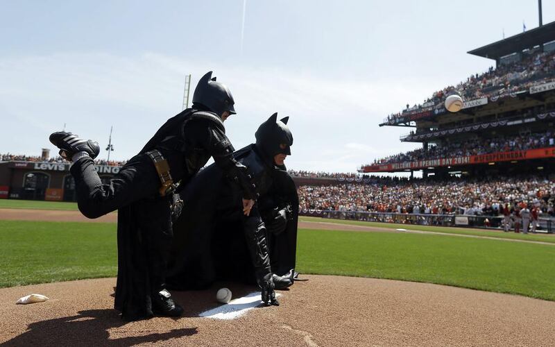 Miles Scott, left, dressed as Batkid, throws the ceremonial first pitch next to Batman before an opening day baseball game between the San Francisco Giants and the Arizona Diamondbacks in San Francisco on Tuesday, April 8, 2014. Eric Risberg /AP