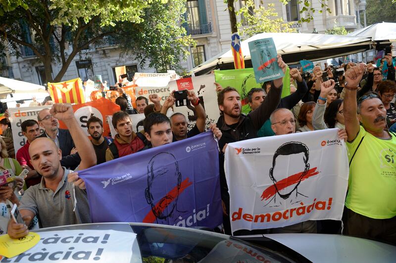 People hold placards reading "Democracy" as they protest in front of the Economy headquarters of Catalonia's regional government in Barcelona on September 20, 2019, during a search by Spain's Guardia Civil police.

The operation comes amid mounting tensions as Catalan leaders press ahead with preparations for an independence referendum on October 1 despite Madrid's ban and a court ruling deeming it illegal.

 / AFP PHOTO / Josep LAGO