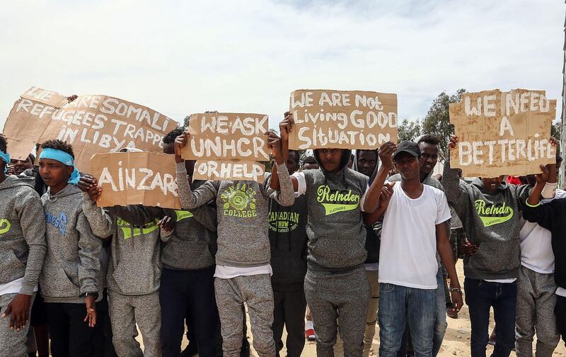 Migrants hold placards during Antonio Guterres's visit to Ain Zara detention centre for migrants. AFP