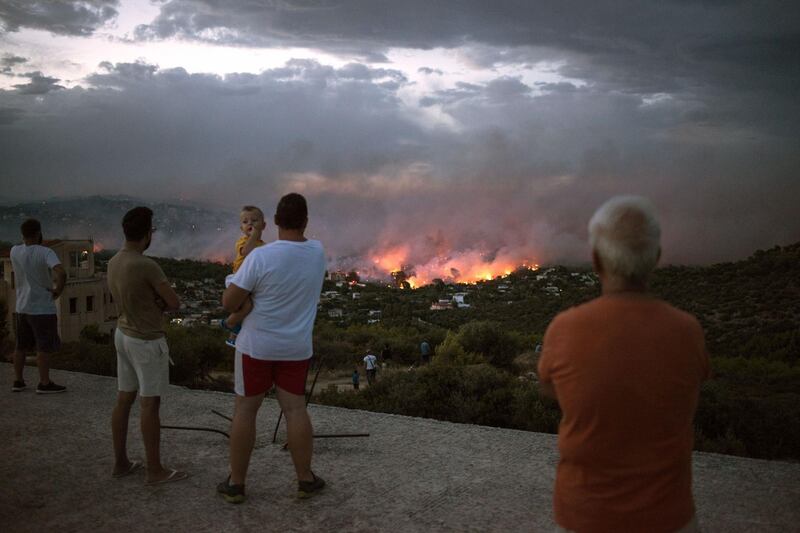 People watch a wildfire in the town of Rafina, near Athens. AFP