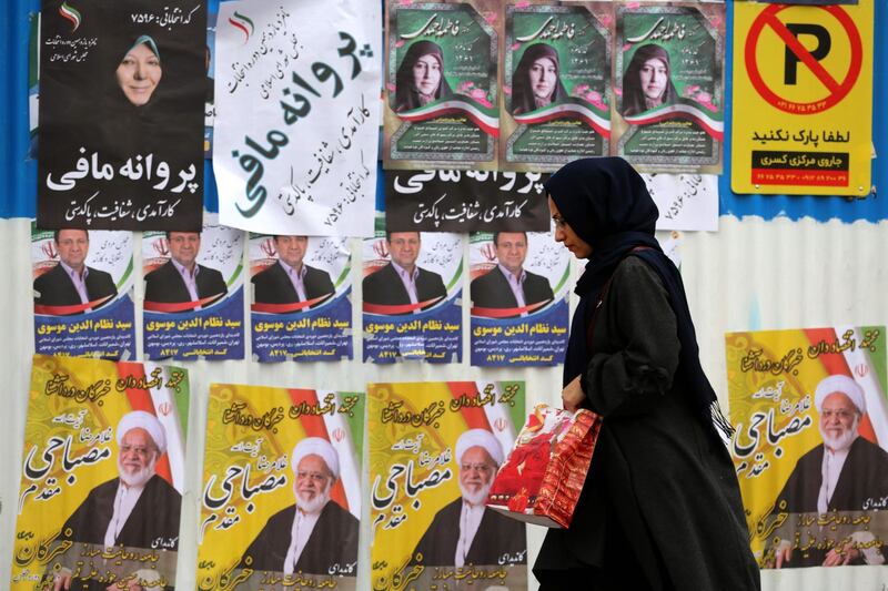 An Iranian woman walks past electoral posters. AFP