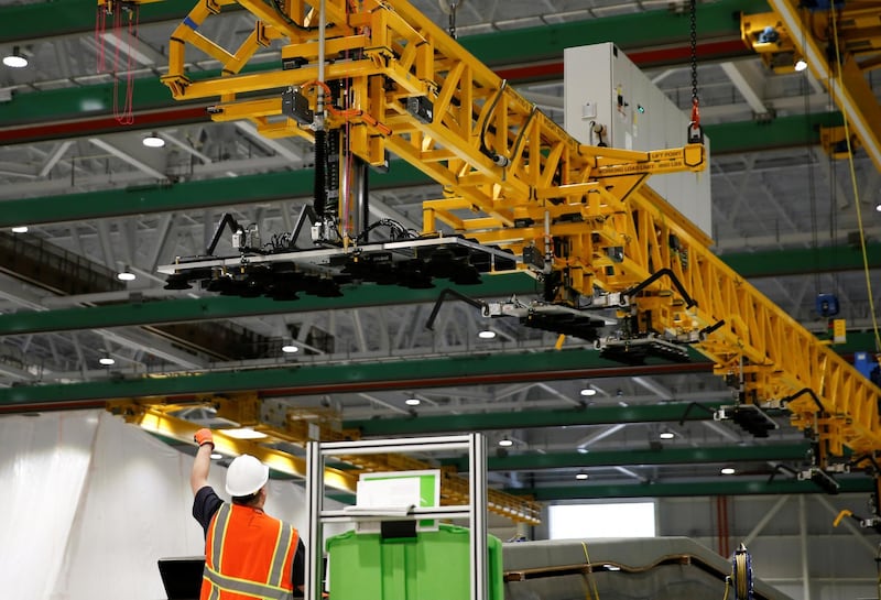 An employee directs an overhead crane used to move large parts around the facility.
