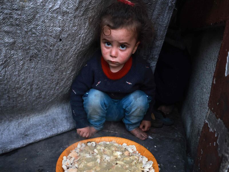 A Palestinian child sits next to a plate of food before an iftar meal at a shelter for displaced people in Rafah, southern Gaza. AFP