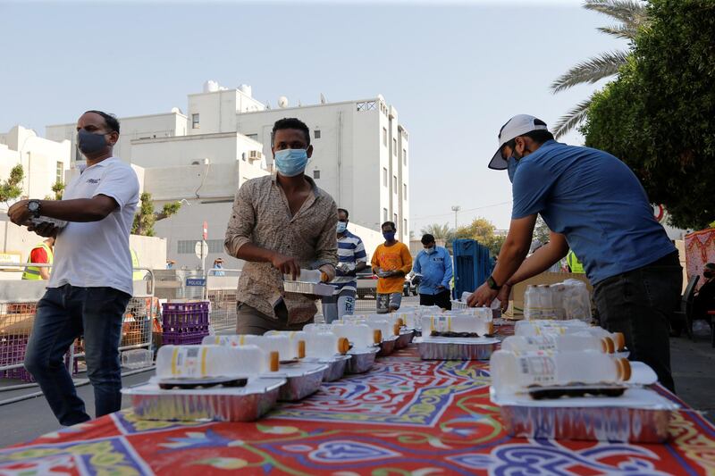 People, wearing face masks and maintaining social distance, receive meals from Adliya Charity during Ramadan, in Manama, Bahrain. Reuters