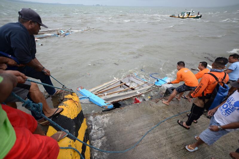 Members of the Philippine Coast Guard haul in the wreckage of boat on Sunday, which capsized off the coast of Guimaras Island a day earlier, in Visayas Region. According to reports, at least two dozen 26 passengers were killed after three motorised boats capsized  amid bad weather conditions. Leo Solinap / EPA