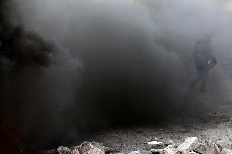 A Palestinian protester holds a tire during clashes with Israeli forces intervening with tear gas during a protest against Israel in the West Bank City of Ramallah. EPA