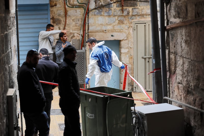 A member of the police's forensics team seals off an alley near the scene.