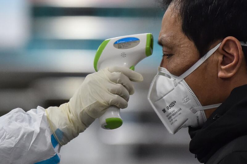 A medical staff member (L) wearing protective clothing to help stop the spread of a deadly virus which began in the city, takes the temperature of a man (R) at the Wuhan Red Cross Hospital in Wuhan.  AFP