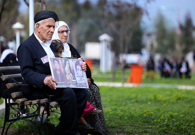 An Iraqi Kurd family holds images of loved ones as they visit in a grave yard for the victims of a gas attack by former Iraqi president Saddam Hussein in 1988.