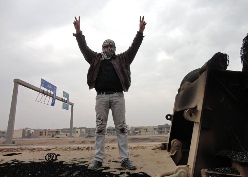 A man shows off the V-sign for victory as he stands on top of a burned-out lorry on the side of the main highway leading west out of Baghdad towards Fallujah on January 5, 2014. The lorries were destroyed during fighting the day before between Iraqi army forces and militants. Sadam El Mehmedy / AFP 

