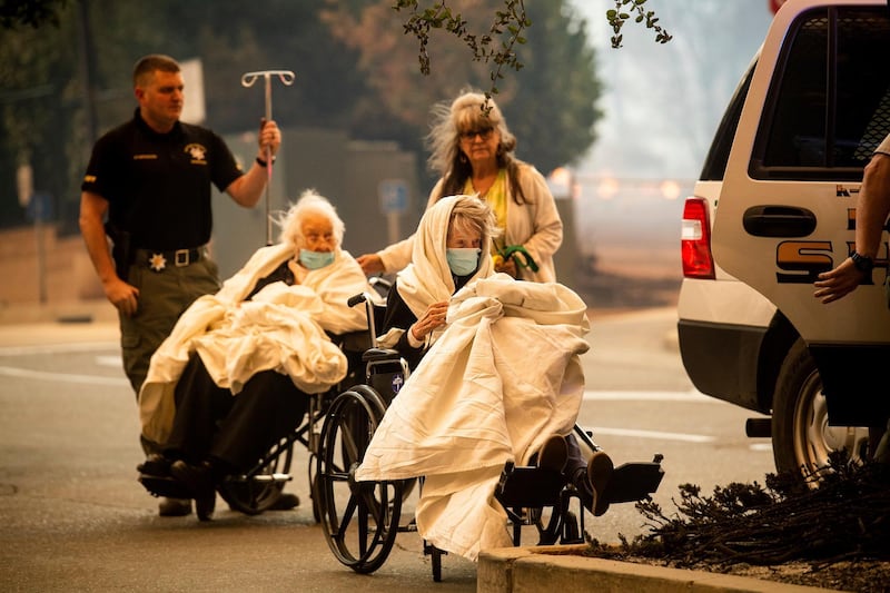 Emergency personnel evacuate patients as the Feather River Hospital burns. AP Photo