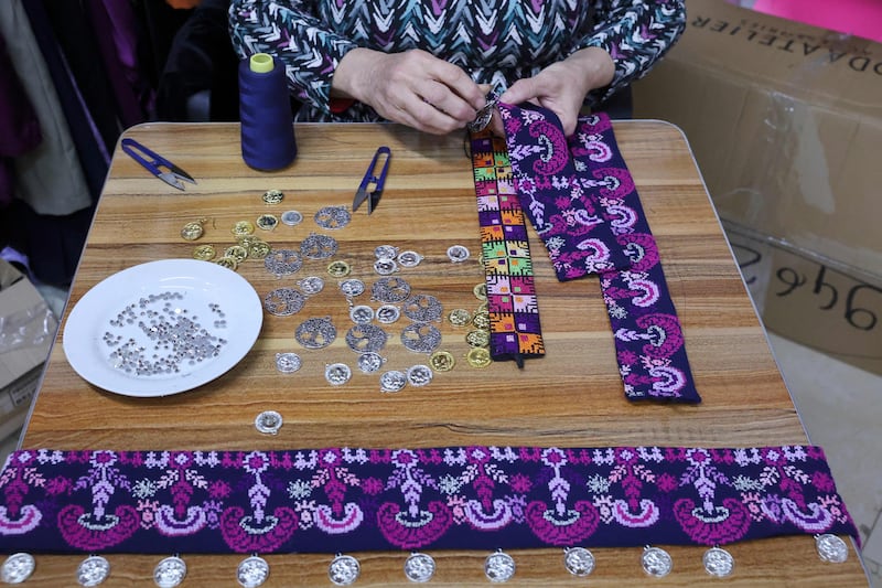 An employee embellishes embroidered strips of fabric at the shop in Beit Sahour.