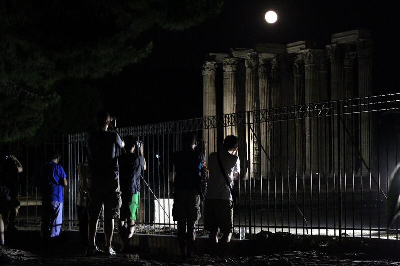 epa03757202 Tourists take pictures of the Temple of Zeus as a full moon rises, in Athens, Greece, 23 June 2013. The 'supermoon' filled the sky on 23 June and looked 14 per cent bigger and 30 per cent brighter than normal, which is the closest approach to Earth.  EPA/PANTELIS SAITAS *** Local Caption ***  03757202.jpg
