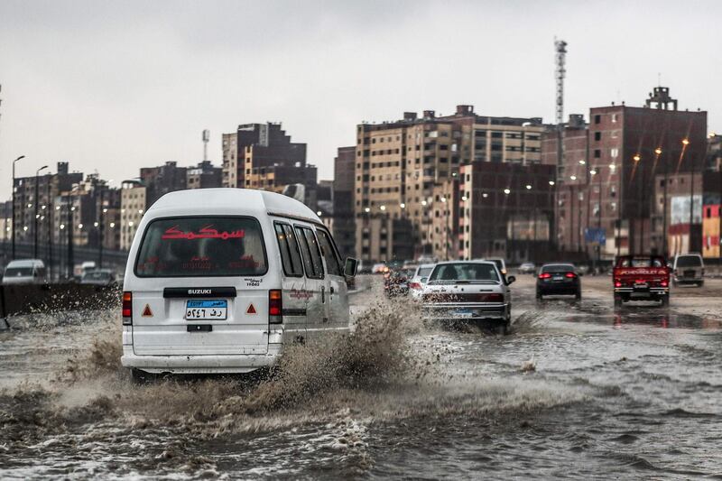 Vehicles drive along a flooded portion of the ring-road highway that encircles the Egyptian capital Cairo and it's twin city of Giza, in Giza on March 12, 2020, amdist a heavy rain storm.  / AFP / Mohamed el-Shahed
