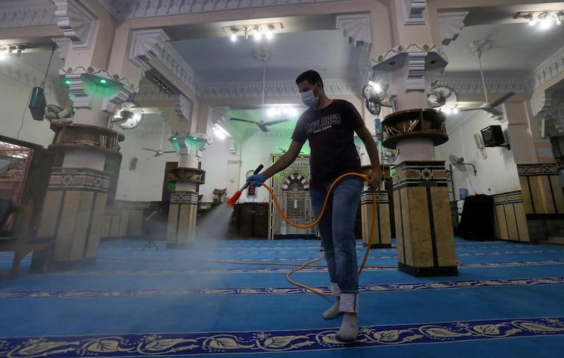 A volunteer wearing a face mask sprays disinfectant inside a mosque before it reopens to the public after three months.  Reuters