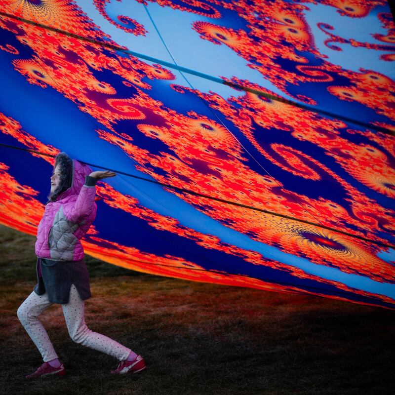 A youngster helps lift a hot air balloon skyward. AP Photo