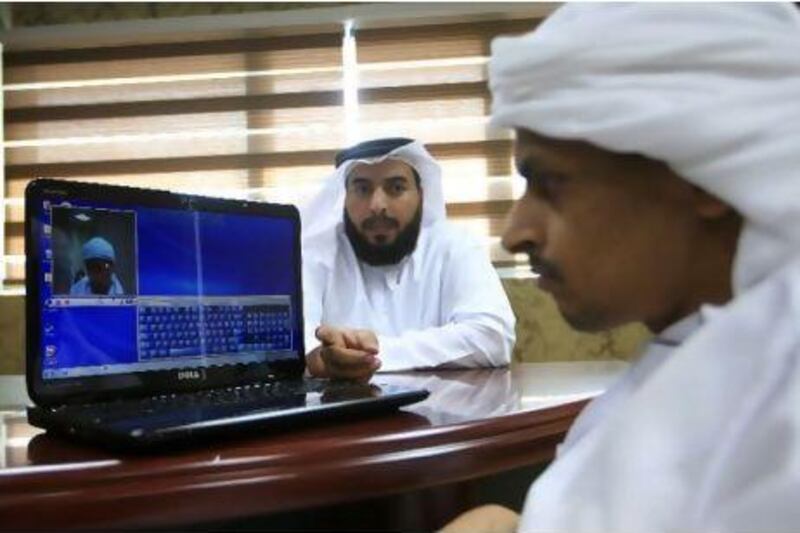 Hashim Abdullah Al Musaabi, left, of SmartSoft, the firm that invented the iMouse, explains to Mohammed Al Tamimi how to operate the mouse with a wink. Ravindranath K / The National