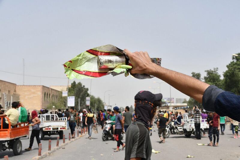 An Iraqi protester holds a smoke grenade fired by security forces amid clashes following an anti-government demonstration in Iraq's southern city of Nasiriyah in Dhi Qar province. AFP