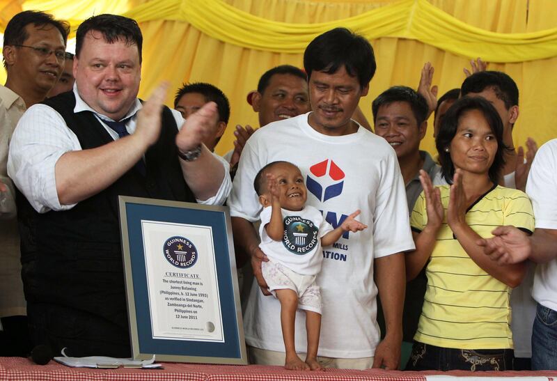 epa02776243 Craig Glenday of Guinness World  Records (L) celebrates with Junrey Balawing, who is celebrating his 18th birthday (C) standing next to a Guinness World  Records ceritificate, crowned as the shortest living man during a ceremony inside a municipal hall in Sindangan, Zamboanga del Norte, southern Philipipines on 12 June 2011. Junrey, a 23.59 inches or 59.93 centimeters tall , who struggles to walk and can't stand too long, replaced Nepalese Khagendra Megar, who stands 26.4 inches for distinction. 'We are very proud of him,' said his mother Concepcion.  EPA/DENNIS M. SABANGAN *** Local Caption ***  02776243.jpg