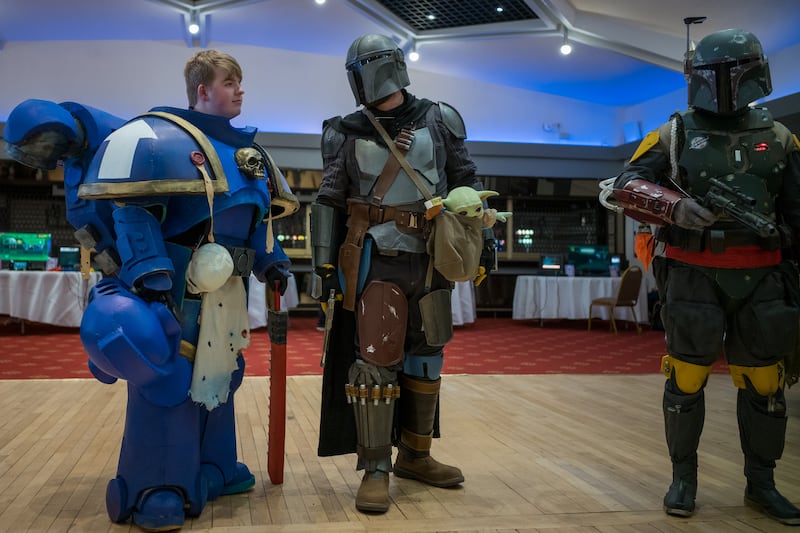 Visitors in costumes, including a Mandalorian, centre, wait to take part in a costume competition on day one