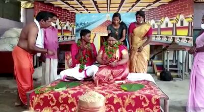 The bride and groom sit with garlands around their necks for their wedding rituals after they floated to a temple in a cooking vessel on a flooded road. Screengrab/Reuters