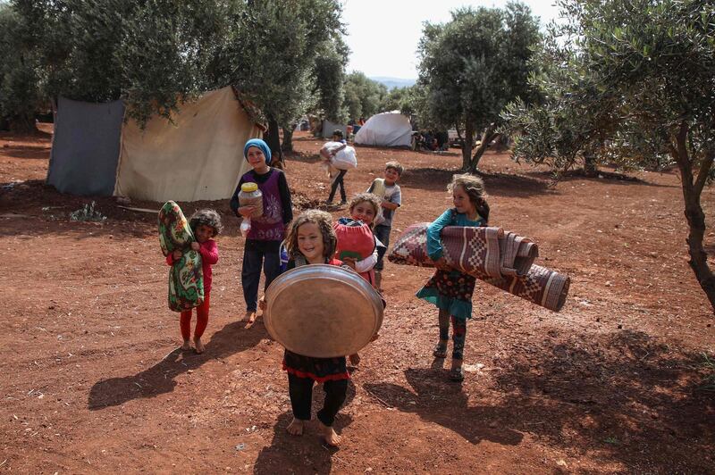 Displaced Syrian children move their belongings to a new spot, after sharing a tent with another family, in a field near a camp for displaced people at the village of Atme, in the northern Idlib province.  AFP