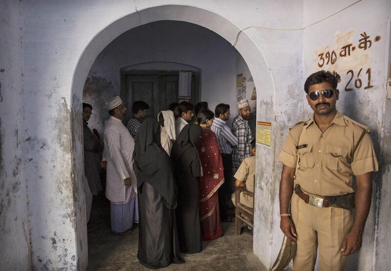 An Indian police officer stands guard as voters wait at a polling station in Varanasi, India. Kevin Frayer / Getty