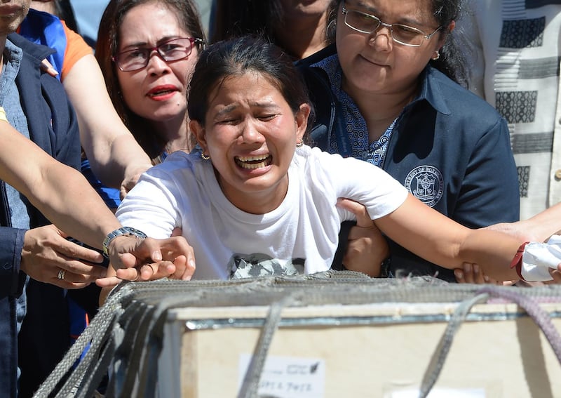 Jessica (C), sister of Filipina worker Joanna Demafelis whose body was found inside a freezer in Kuwait, cries in front of the wooden casket containing her sister shortly after arriving at the international airport in Manila on February 16, 2018.
The Philippines on February 12 expanded a ban on its citizens working in Kuwait after President Rodrigo Duterte angrily lashed out at the Gulf state over reports of Filipino workers suffering abuse and exploitation. Authorities say 252,000 Filipinos work in Kuwait, many as maids, yet domestic workers there are not covered by ordinary labour legislation. / AFP PHOTO / TED ALJIBE