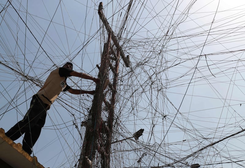 An Iraqi man connects overhead cables providing generator electricity to homes and businesses who can afford it in Sadr City, east of the capital Baghdad, amid power outages and soaring temperatures.  AFP
