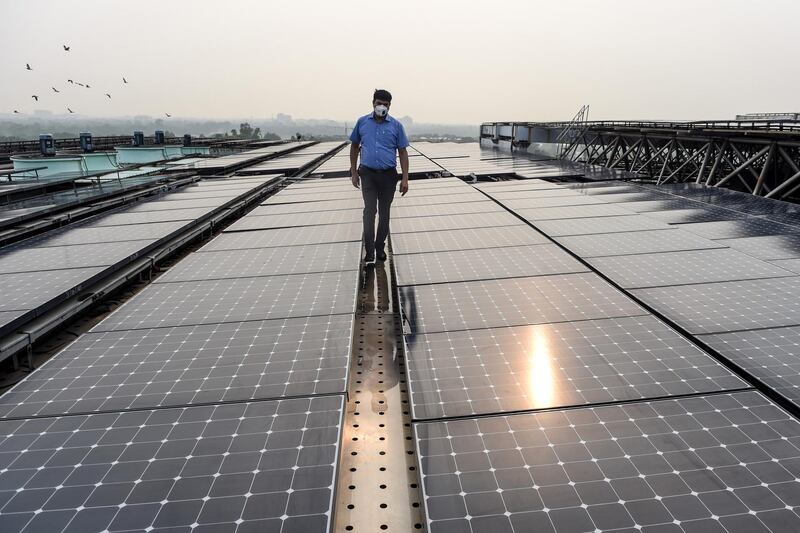 In this photograph taken on July 17, 2020, an employee walks among solar panels installed on the building of Indira Paryavaran Bhawan or the Indian Environment Ministry in New Delhi. (Photo by Money SHARMA / AFP)