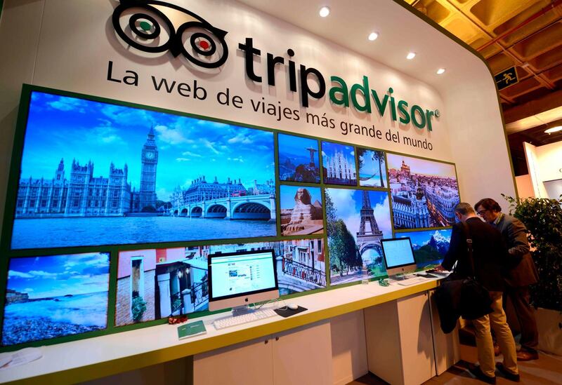 (FILES) In this file photo taken on January 22, 2014 visitors watch documents at the stand of TripAdvisor during the International Tourism Trade Fair (FITUR) in Madrid. TripAdvisor does not clean up the fake reviews that artificially boost the reputation of top rated hotels, according to a survey of the British consumer association Which? / AFP / GERARD JULIEN
