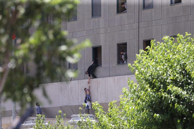 Iranian policemen help civilians escape out the parliament building fleeing. Omid Wahabzadeh / EPA