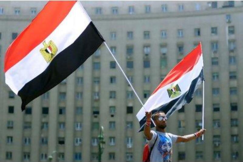 An Egyptian man waves two national flags during a protest in Cairo's Tahrir Square on Sunday, vowing to keep up their sit-in which began on July 8, despite a series of concessions by the Egyptian prime minister. Mohammed Hossam / AFP Photo