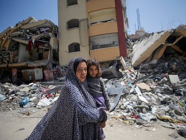 A Palestinian woman holds her daughter as she walks past destroyed buildings in the north of Al Nusairat refugee camp, southern Gaza Strip, 29 April 2024. EPA